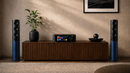 Audio equipment including speakers and a receiver on a wooden cabinet against a beige wall.